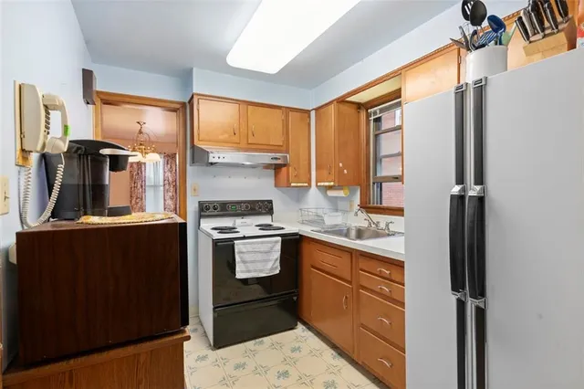 a kitchen with stainless steel appliances granite countertop a refrigerator a stove and a sink with wooden floor