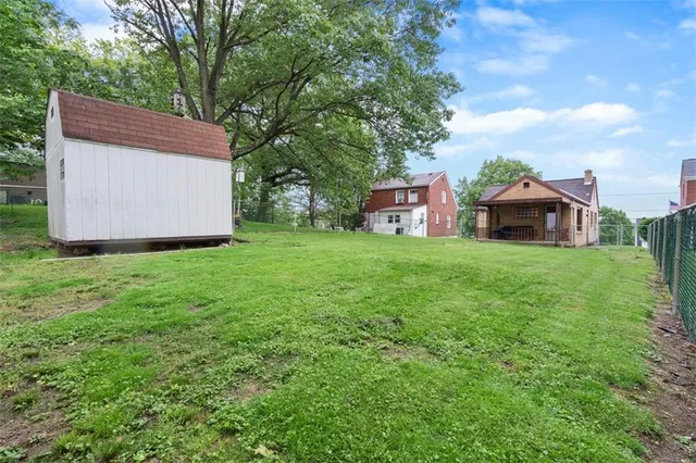 a backyard of a house with table and chairs and a large tree
