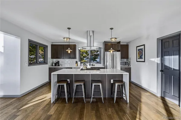 a kitchen with stainless steel appliances a dining table chairs and wooden floor
