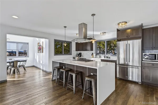 a kitchen with stainless steel appliances a kitchen island hardwood floor sink stove and wooden cabinets