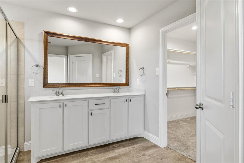 915 Timber Ridge Drive Justin, TX 76247 - Photo 22 of 39 Bathroom featuring a dual vanity with white cabinetry, a large framed mirror, and a glass-enclosed shower