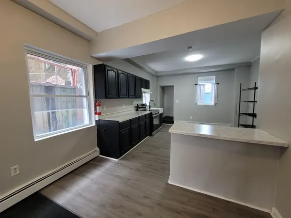 a large kitchen with stainless steel appliances granite countertop a stove a sink and a granite countertops with wooden floor