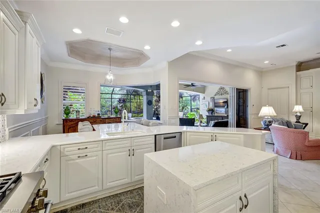a large white kitchen with a stove a sink a refrigerator and white cabinets with wooden floor
