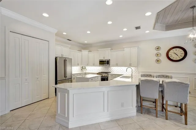 a kitchen with a sink a refrigerator and chairs