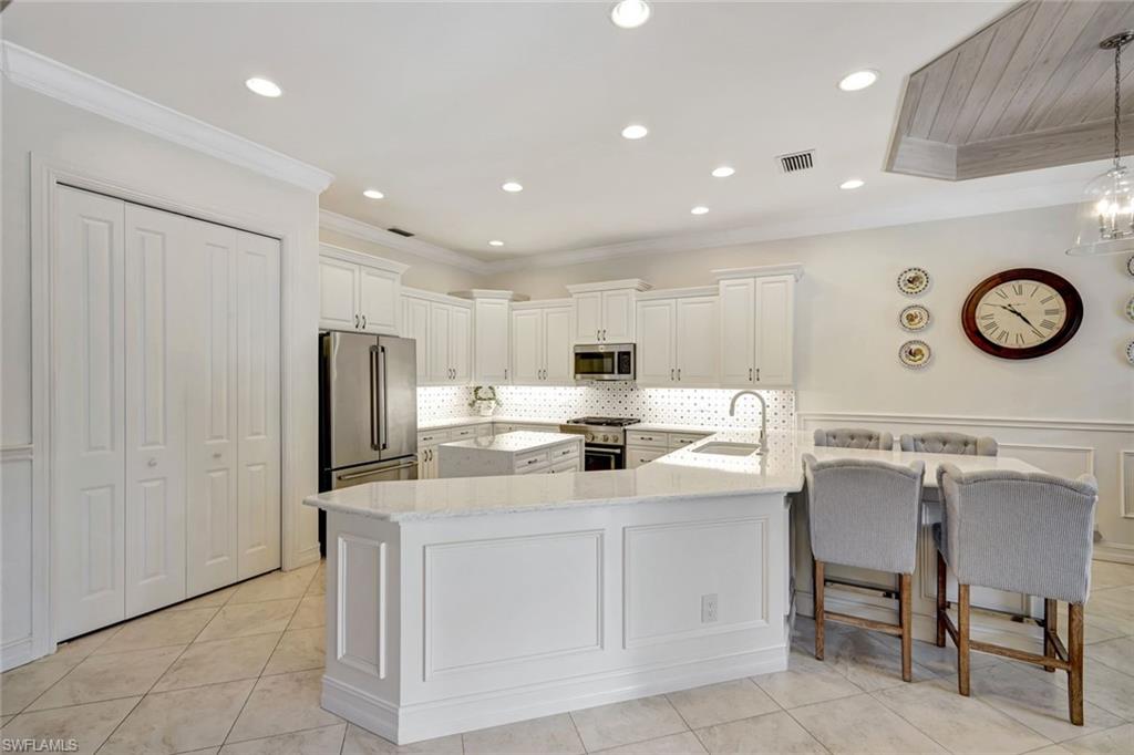12441 Villagio Way Fort Myers, FL 33912 - Photo 13 of 32 a kitchen with a sink a refrigerator and chairs