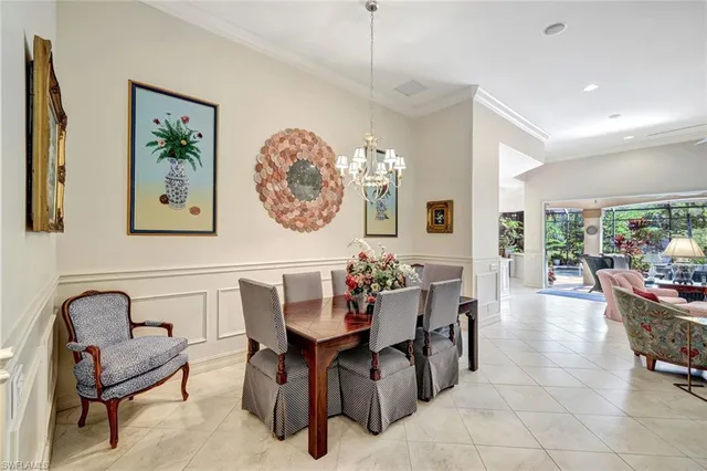 a view of a dining room and livingroom with furniture a rug a painting and a chandelier