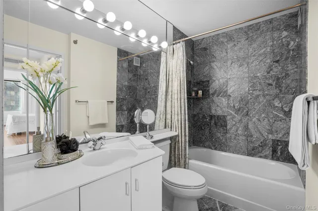 a bathroom with a sink a toilet a mirror a bathtub and shower