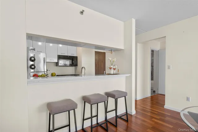 a kitchen with stainless steel appliances a microwave a stove and white cabinets with wooden floor