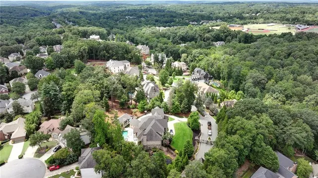an aerial view of a residential houses with outdoor space and trees