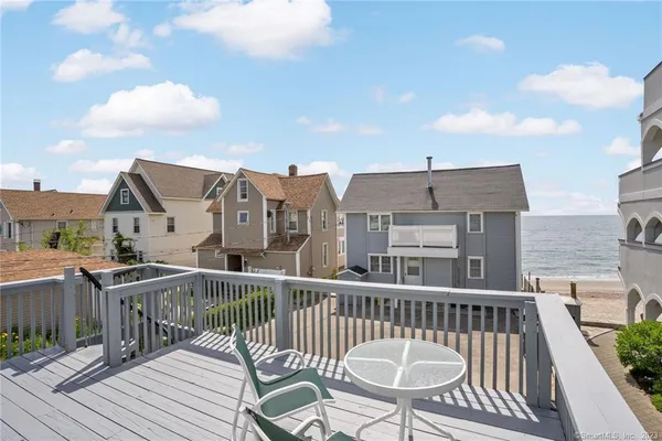 a view of a roof deck with table and chairs with wooden floor and fence