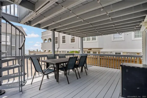 a view of a roof deck with table and chairs with wooden floor and fence