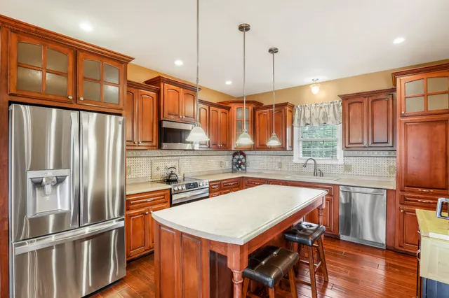 a kitchen with stainless steel appliances granite countertop a refrigerator a sink dishwasher a stove and a refrigerator with wooden floor