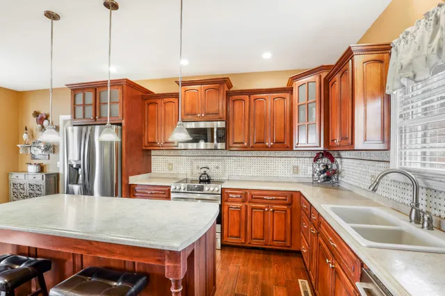 a kitchen with stainless steel appliances granite countertop a sink a refrigerator and wooden cabinets
