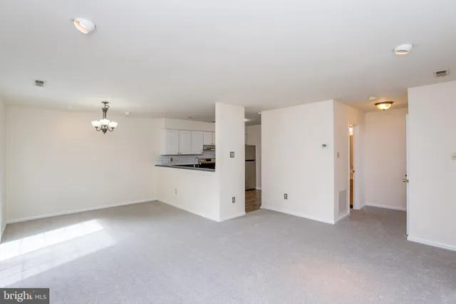 a view of kitchen with refrigerator and white cabinets