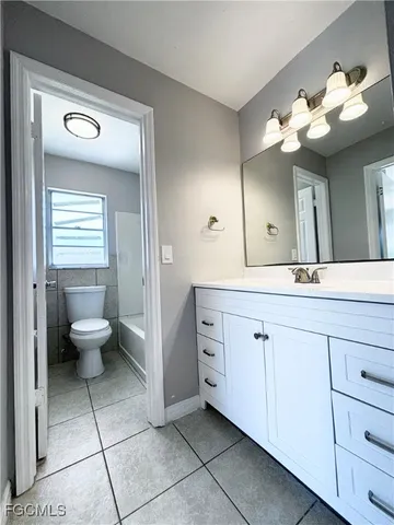 a spacious bathroom with a granite countertop sink a toilet and a mirror