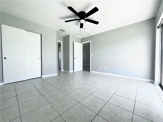 a view of an empty room and chandelier fan