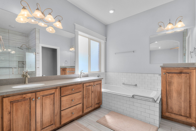 1501 West Elk Circle Mapleton, UT 84664 - Photo 24 of 39 Bathroom featuring a dual vanity with light-toned countertops and wood-finish cabinetry, a large soaking tub with subway tile surround, a spacious walk-in shower with glass enclosure and tiled walls, and a large window providing natural illumination