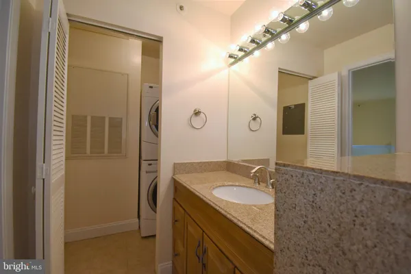 a bathroom with a granite countertop bathtub shower sink vanity and toilet