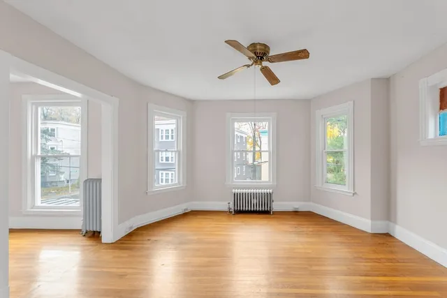 a view of empty room with wooden floor and fan