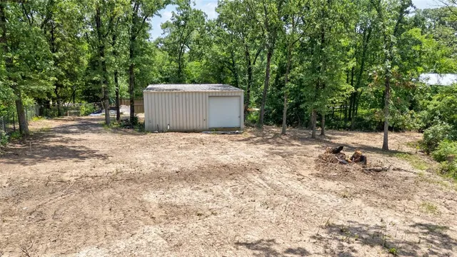 a backyard of a house with a large tree and wooden fence