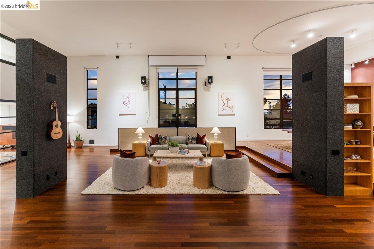 875 Colusa Avenue Berkeley, CA 94707 - Photo 1 of 1 Spacious living area featuring rich wood-finish flooring, white walls, and large windows with dark framing