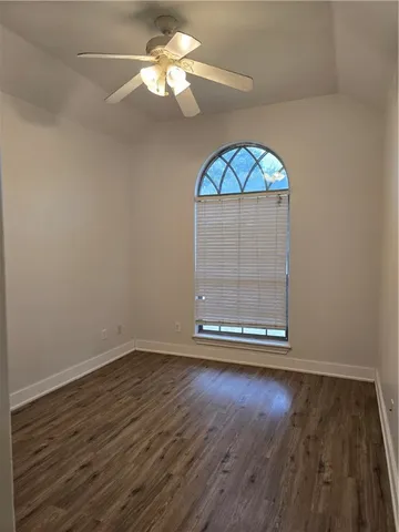 an empty room with wooden floor fan and windows