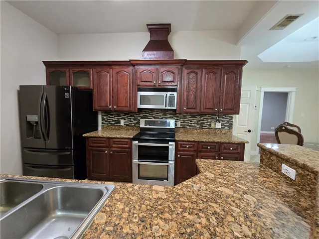 a kitchen with stainless steel appliances granite countertop a refrigerator stove and sink