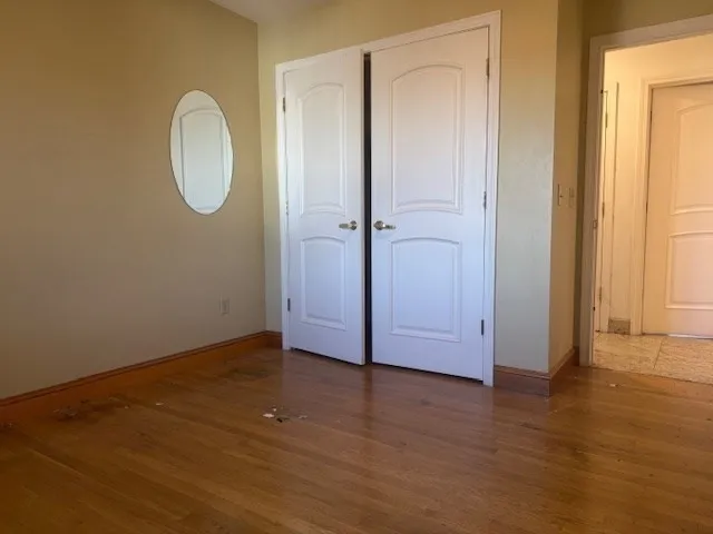 a view of a room with wooden floor and mirror