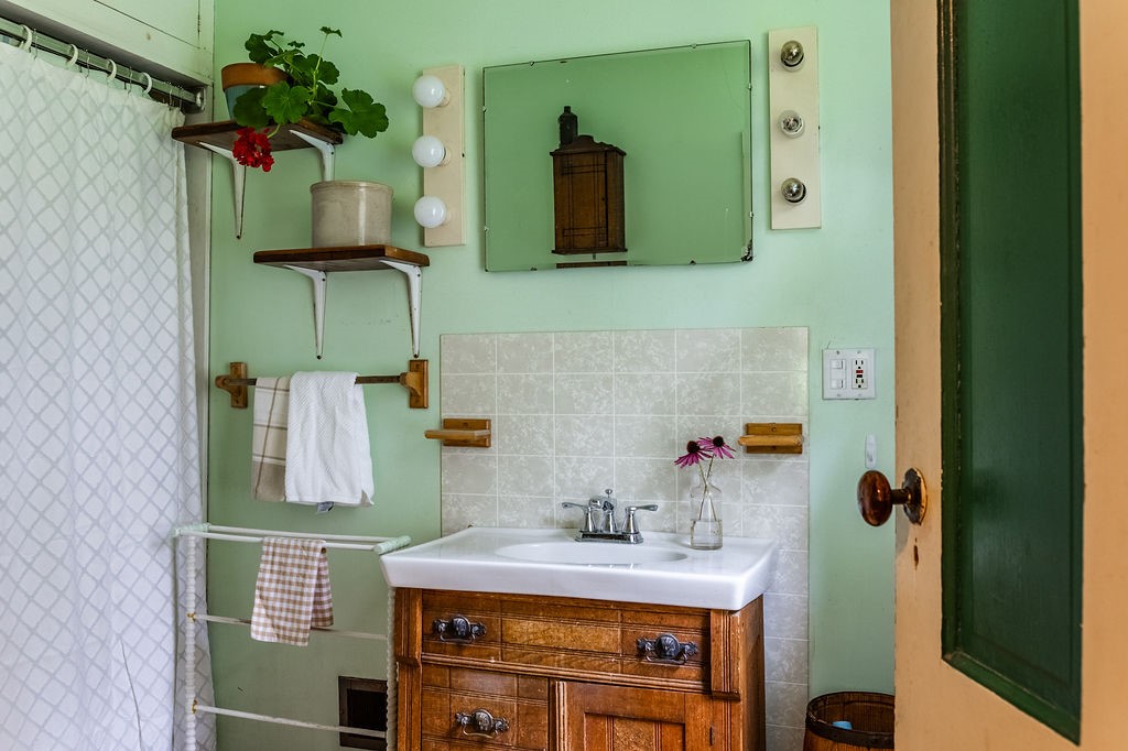67 Fisk Road Bovina, NY 13753 - Photo 21 of 48 A vintage vanity sits beneath a tiled backsplash in this charmingly detailed washroom.