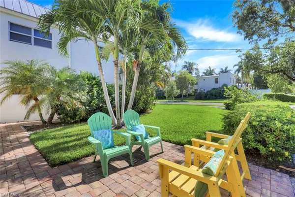 a view of a swimming pool with a lawn chairs under palm trees