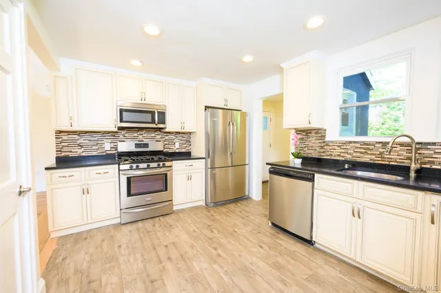 a kitchen with stainless steel appliances granite countertop a stove a sink and a refrigerator
