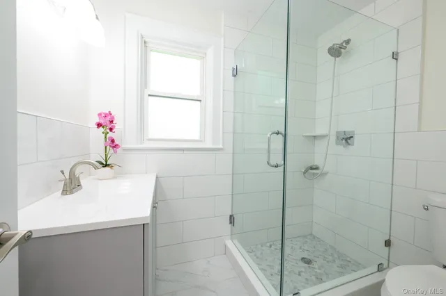 a bathroom with a shower sink mirror and toilet