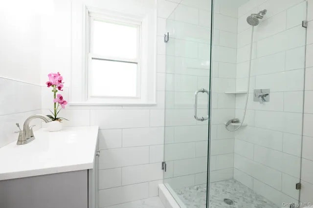 a bathroom with a sink shower and a mirror