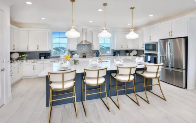 a kitchen with stainless steel appliances kitchen island granite countertop a dining table chairs sink and cabinets