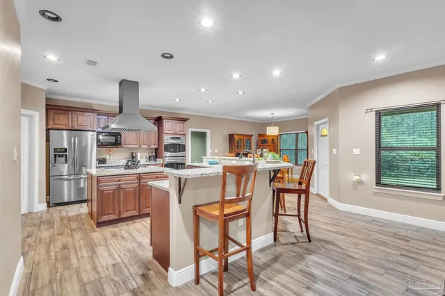 a kitchen with a table chairs wooden floors and a view of living room
