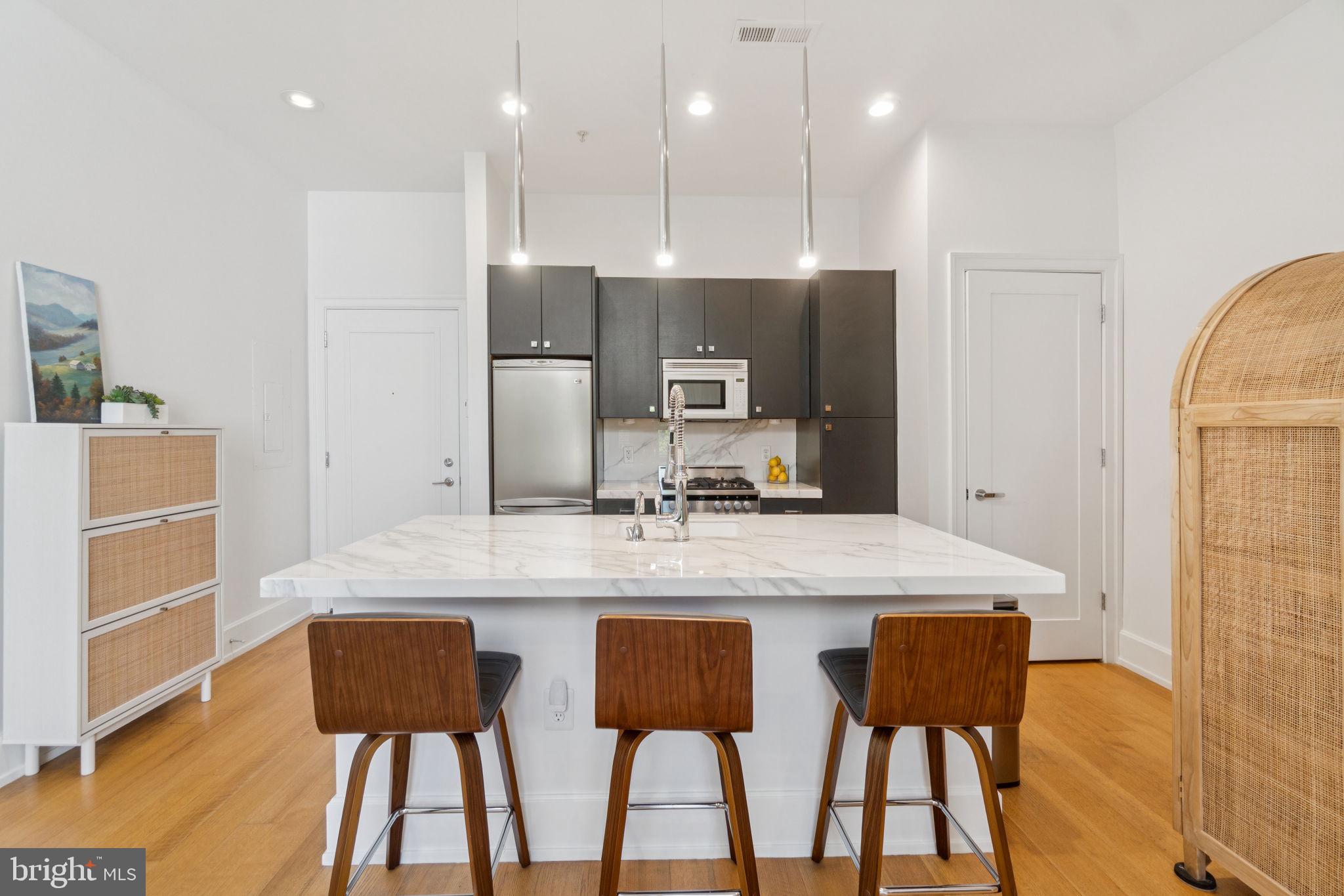 2516 Q Street Northwest, Unit Q206 Washington, DC 20007 - Photo 3 of 16 a kitchen with a dining table chairs cabinets and stainless steel appliances