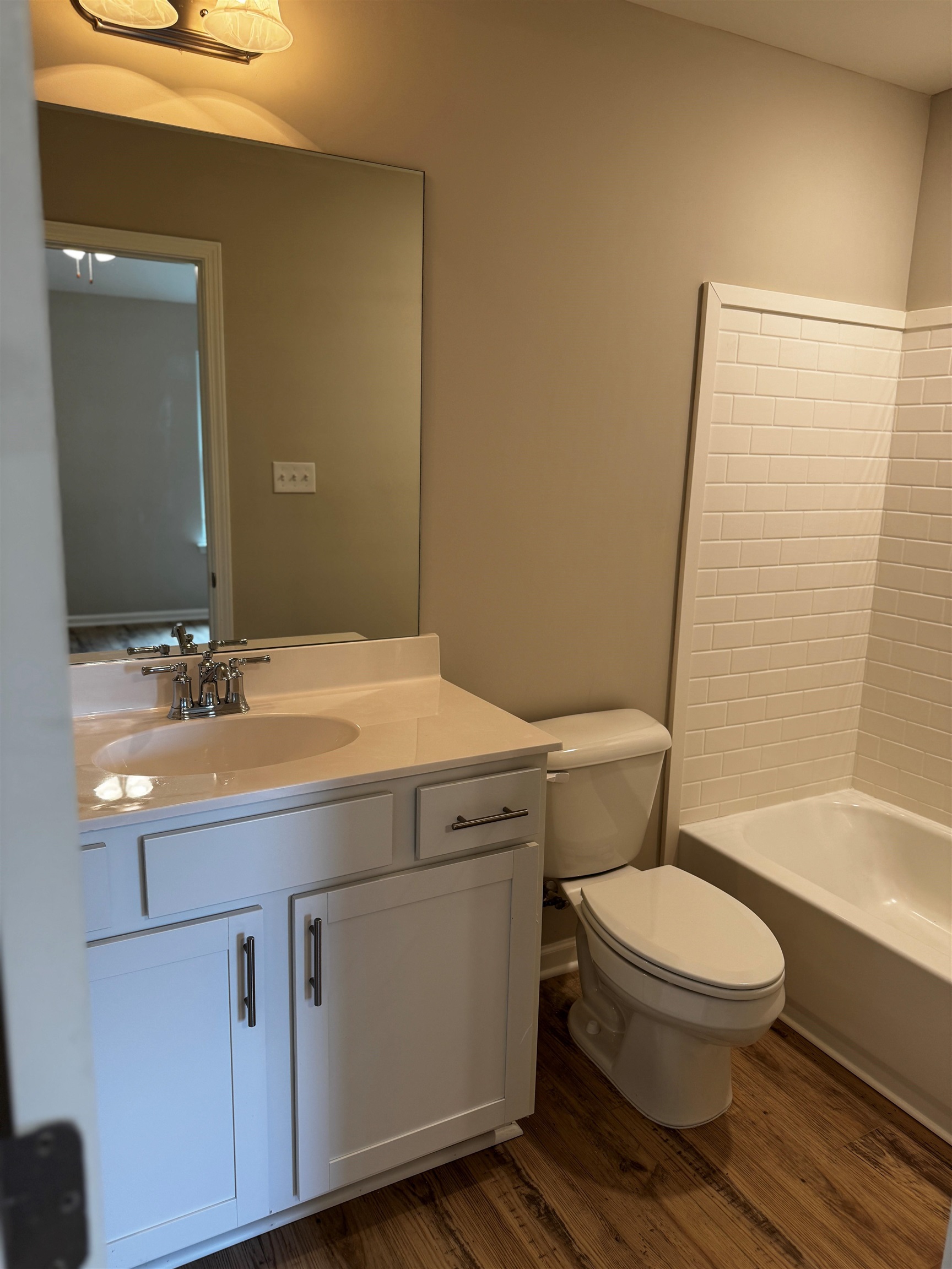 5283 Zodiac Road Memphis, TN 38118 - Photo 7 of 13 Bathroom featuring a white vanity with an integrated sink and chrome fixtures, wood-finish flooring, a toilet, and a bathtub with subway tile surround