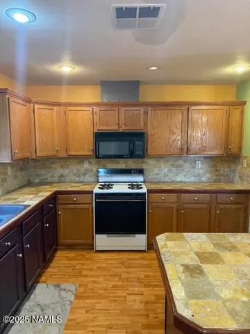 a kitchen with stainless steel appliances granite countertop a stove a sink dishwasher and a microwave oven with white cabinets