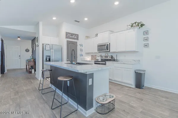 a kitchen with kitchen island granite countertop a sink cabinets and wooden floor