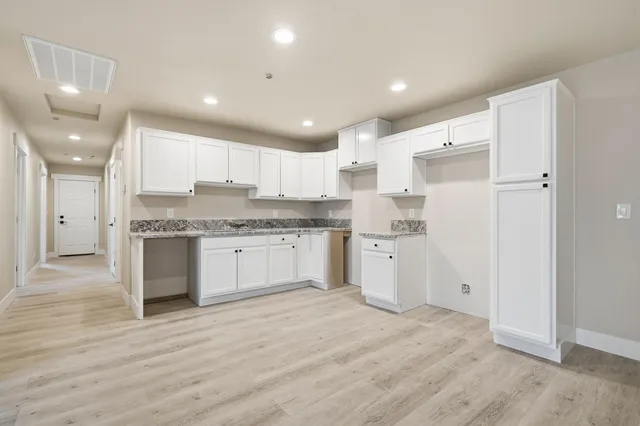 an empty room with ceiling fan and windows
