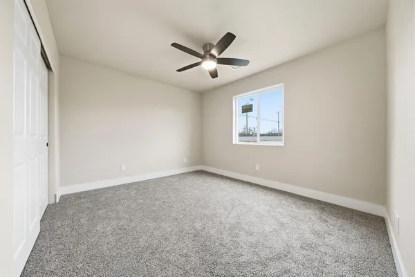 an empty room with ceiling fan and windows