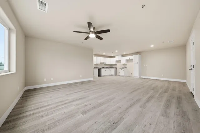 an empty room with window and ceiling fan