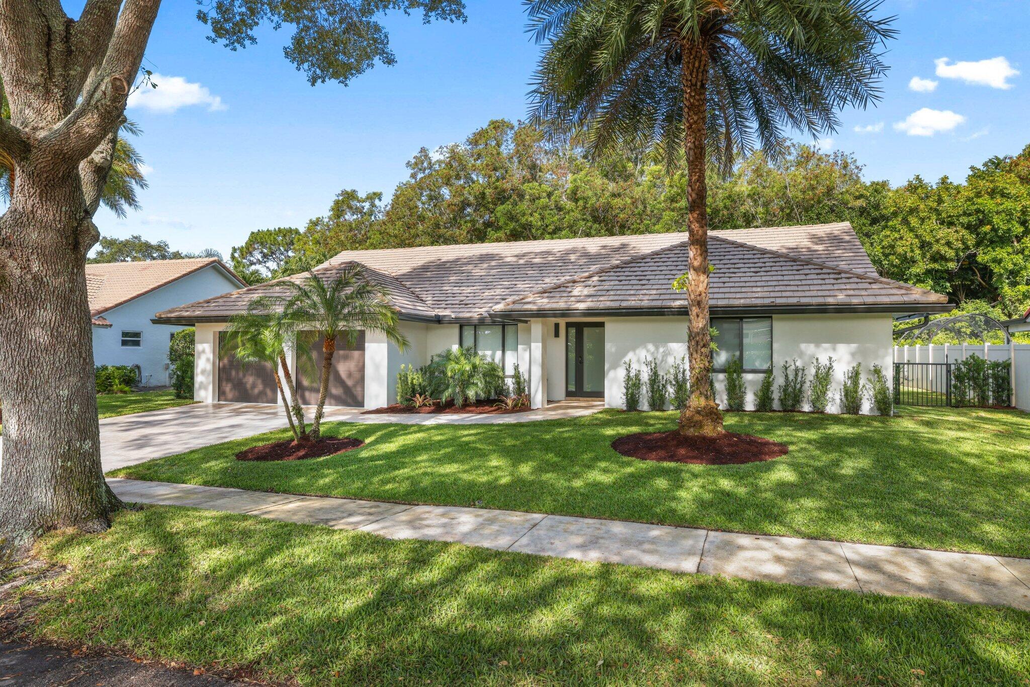 3901 Northwest 27th Avenue Boca Raton, FL 33434 - Photo 2 of 56 a front view of a house with a yard table and chairs
