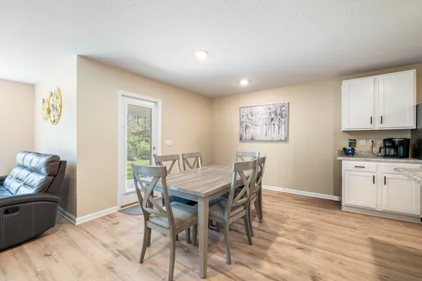 a kitchen with stainless steel appliances granite countertop a stove a sink a refrigerator with a dining table and chairs
