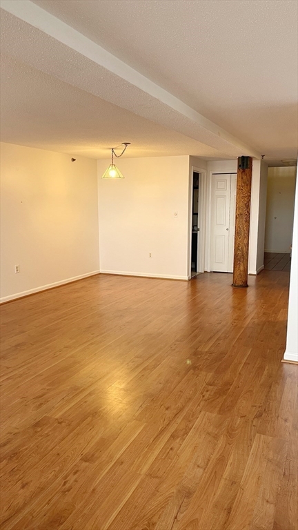 200 Market Street, Unit 505 Lowell, MA 01852 - Photo 12 of 22 a view of an empty room with wooden floor and a window