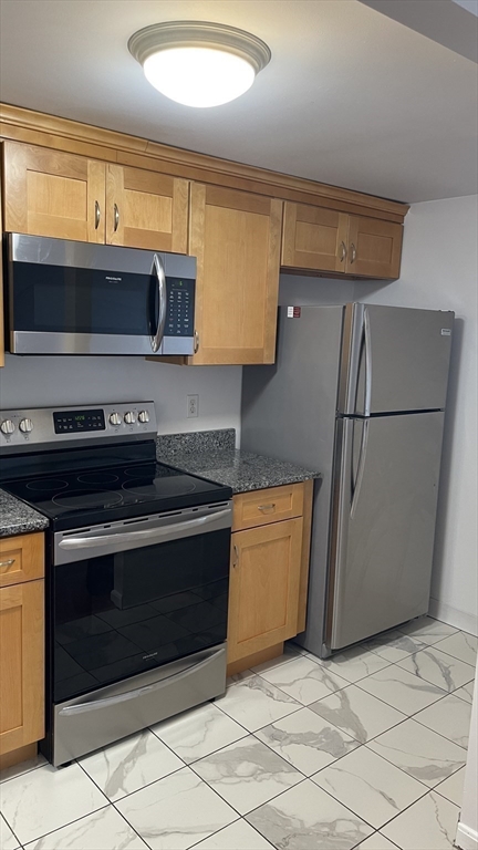 200 Market Street, Unit 505 Lowell, MA 01852 - Photo 15 of 22 a kitchen with stainless steel appliances granite countertop a stove a sink and a microwave