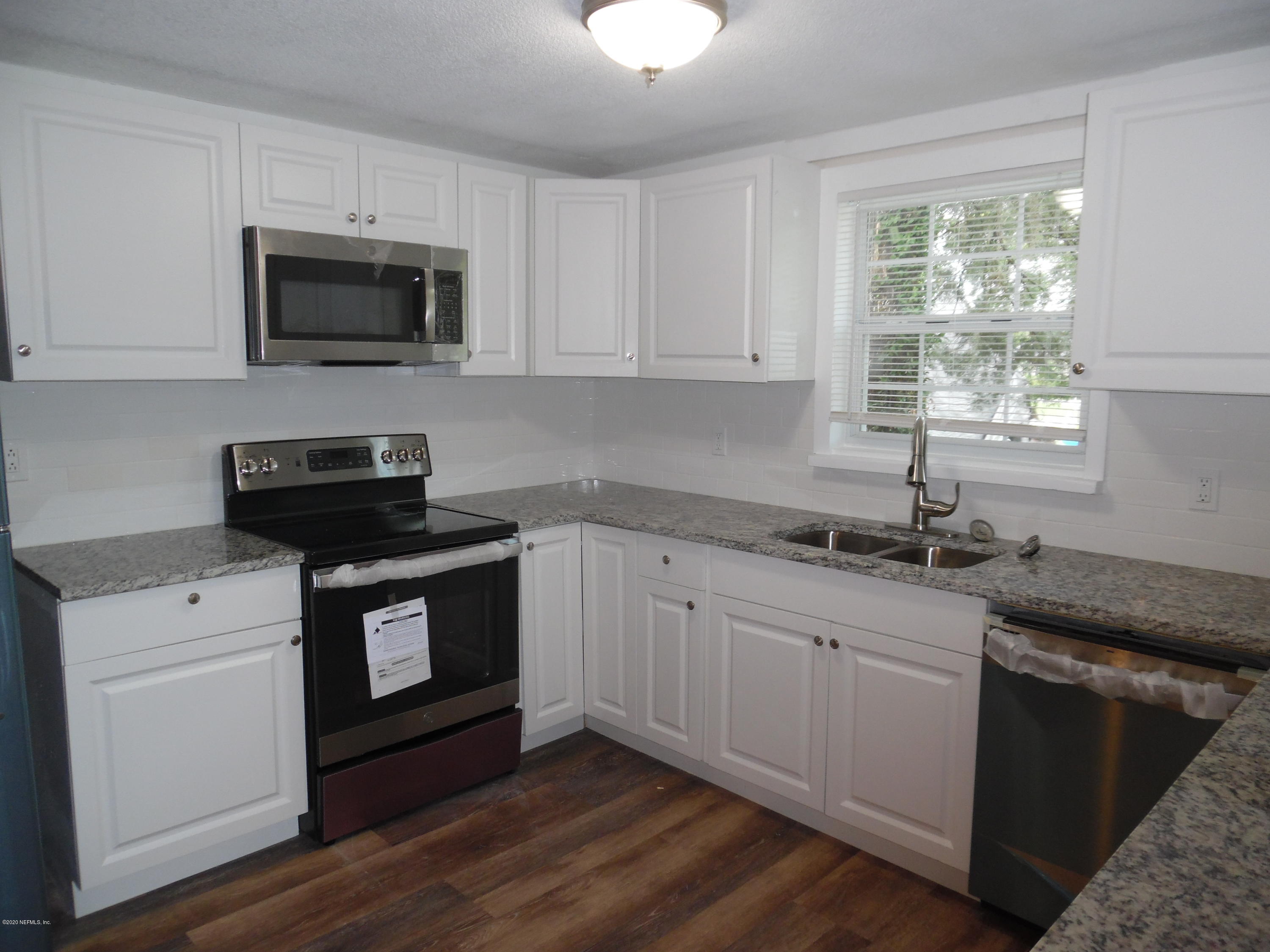 620 Southwest Field Avenue Keystone Heights, FL 32656 - Photo 43 of 68 a kitchen with granite countertop white cabinets appliances a window and a sink
