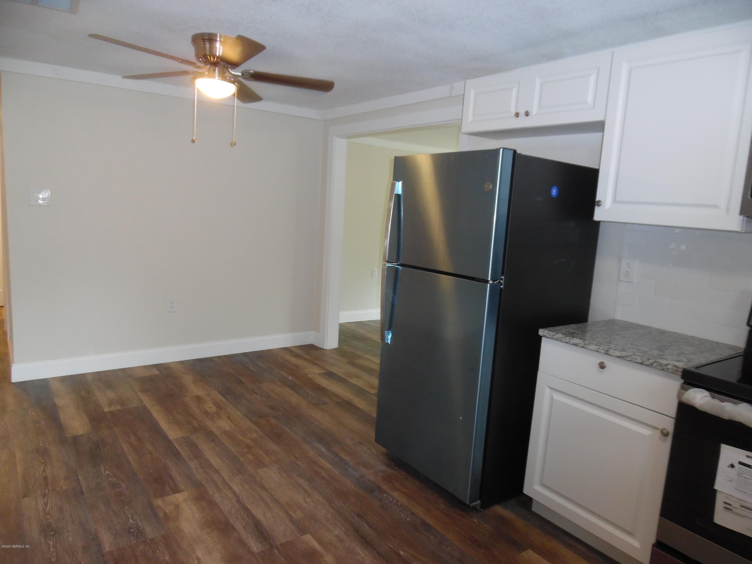 620 Southwest Field Avenue Keystone Heights, FL 32656 - Photo 46 of 68 a view of a refrigerator in kitchen and an empty room with wooden floor