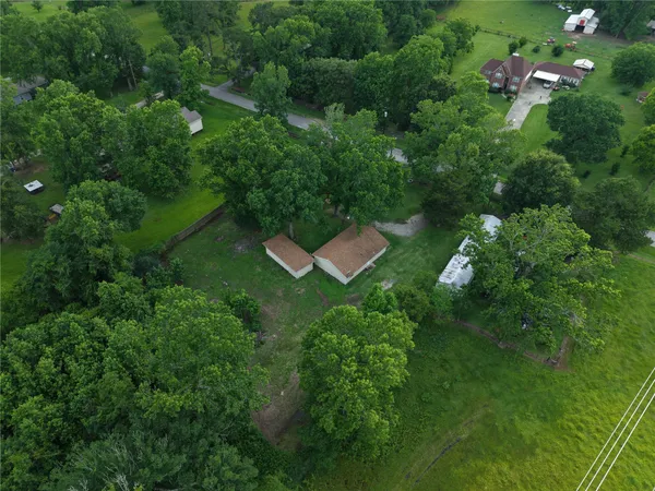 an aerial view of residential house with outdoor space and trees all around