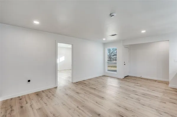 a view of an empty room with wooden floor and windows